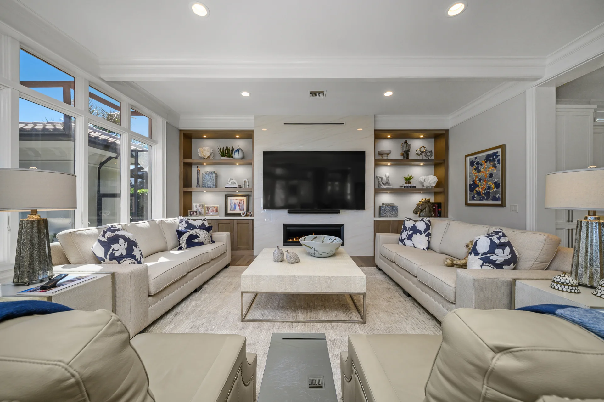 A bright living room featuring white furniture and a cozy fireplace, creating a warm and inviting atmosphere.