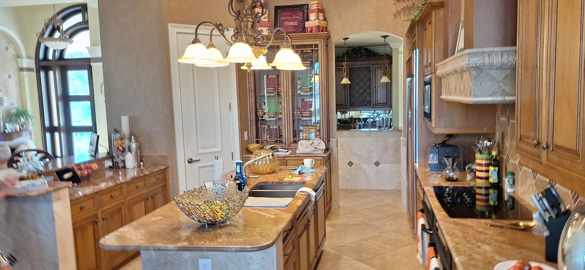 A modern kitchen featuring a spacious island with a sink, surrounded by cabinetry and appliances.