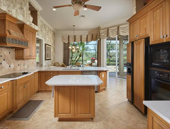 A spacious kitchen featuring wooden cabinets and a ceiling fan, creating a warm and inviting atmosphere.